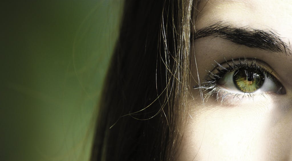A detailed close-up of a woman's eye with green iris, capturing beauty detail.